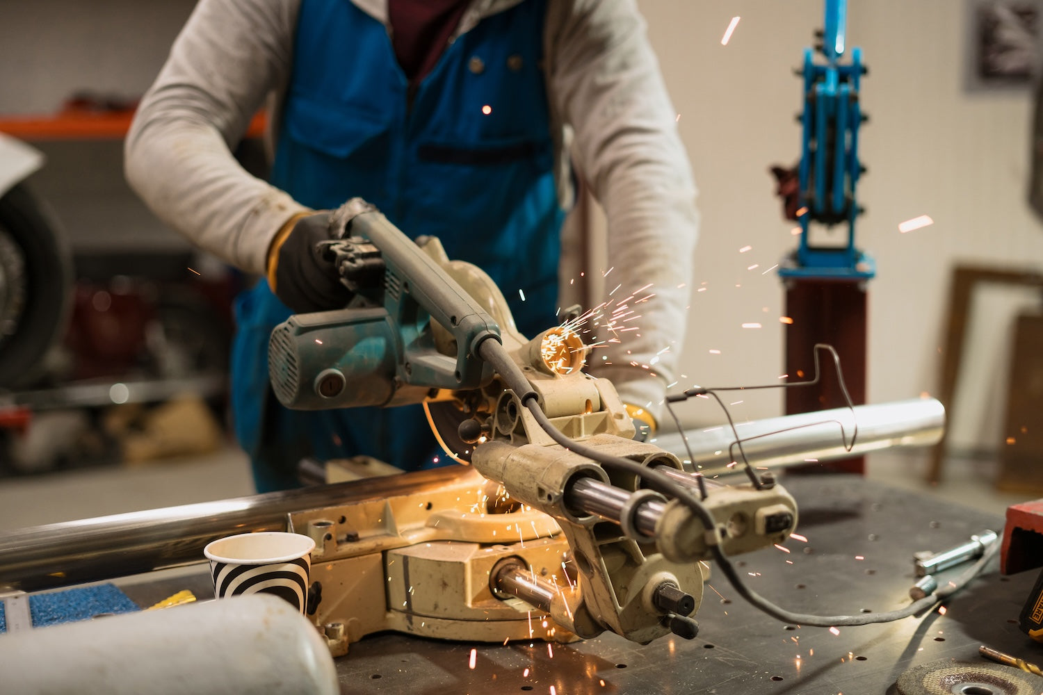 Metal fabrication worker cutting metal rod while wearing cut resistant work gloves, durable metal fabrication gloves and sheet metal gloves for protection.