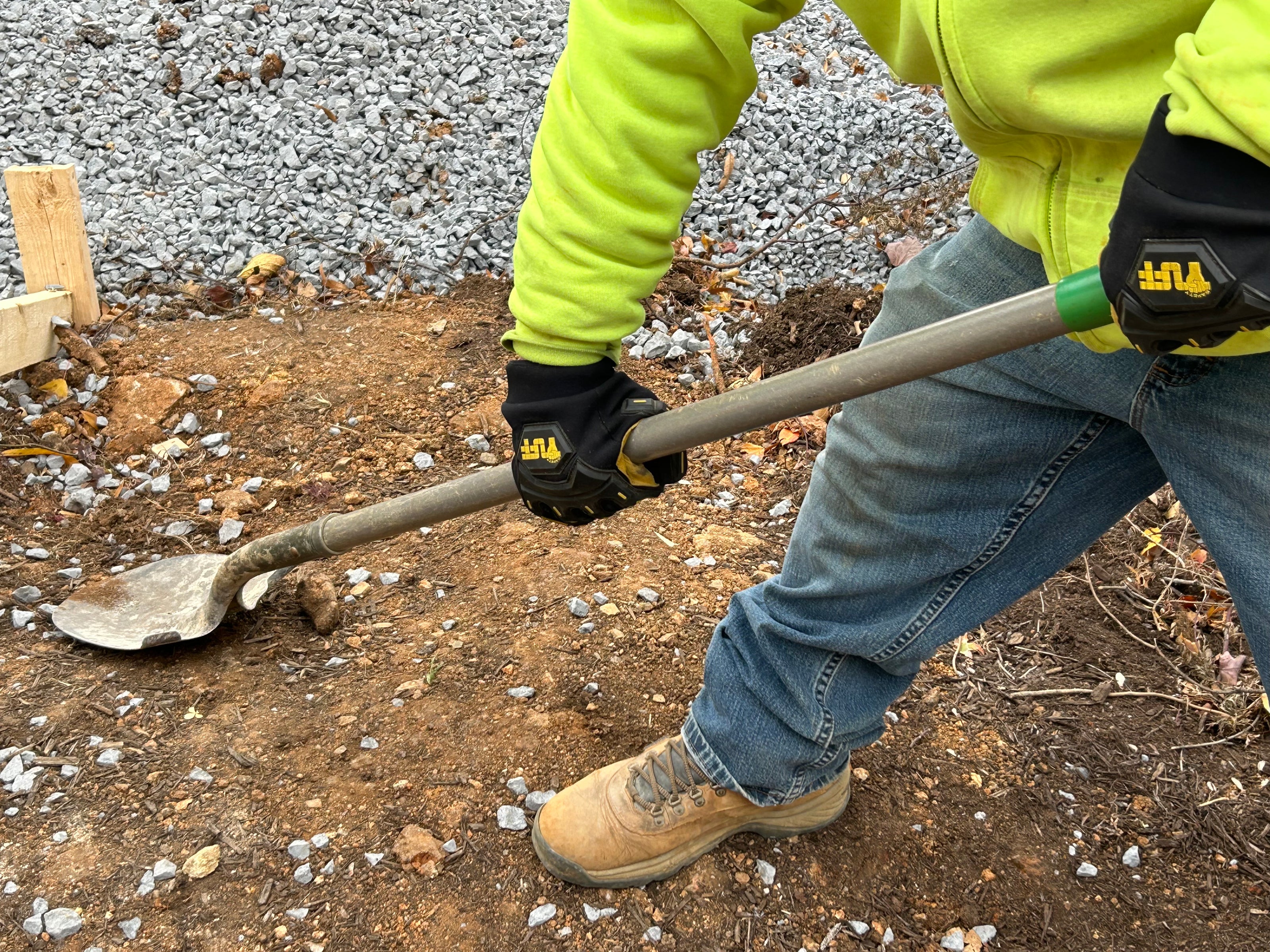 A construction worker wearing Safety TUFF's 1000 impact glove while digging on a job site